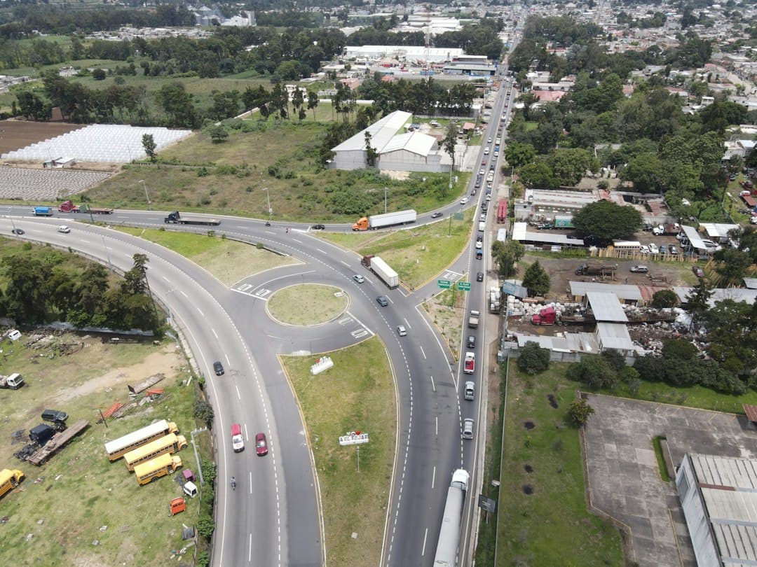 Coches en una carretera junto a casas y árboles durante el día, en el chat de El Tejar