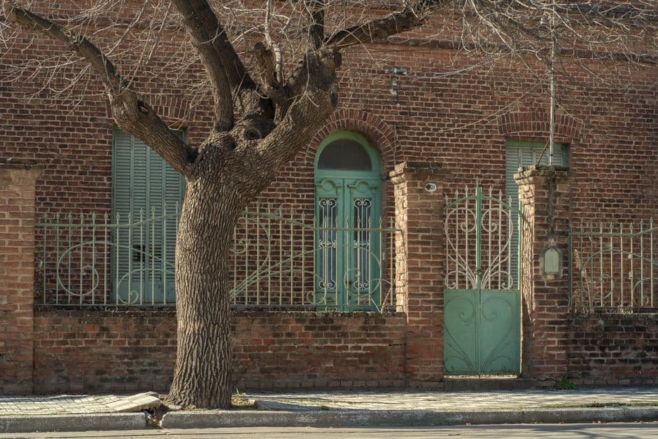 Fachada antigua de ladrillo con una puerta turquesa en Argentina, en el chat de Carlos Casares