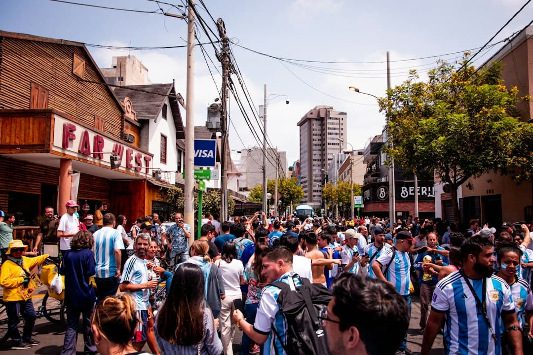 Gente caminando por una calle entre edificios altos, en el chat de Sunchales