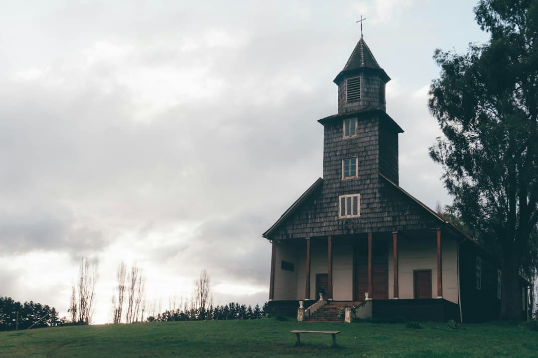 Iglesia con campanario y un banco delante, en el chat de La Cruz