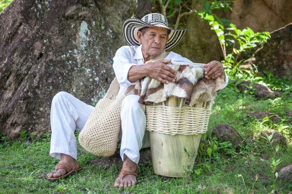 Anciano colombiano sentado en la hierba con un tambor, en el chat de Timbiquí