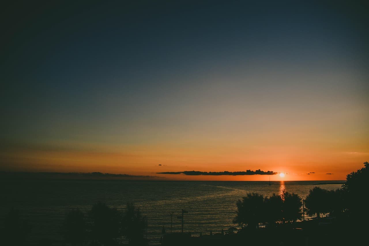 Puesta de sol sobre el agua junto a la orilla, en el chat de Diamante