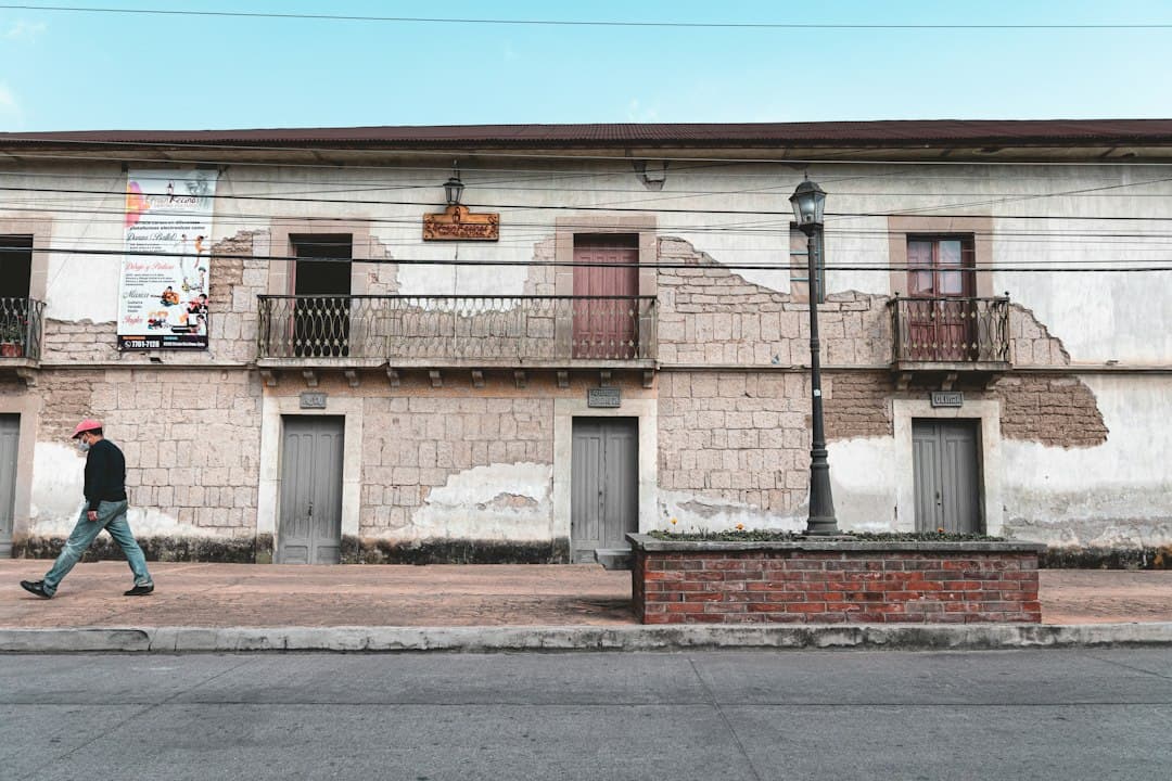 Hombre caminando por la calle frente a un edificio, en el chat de Concepción Chiquirichapa