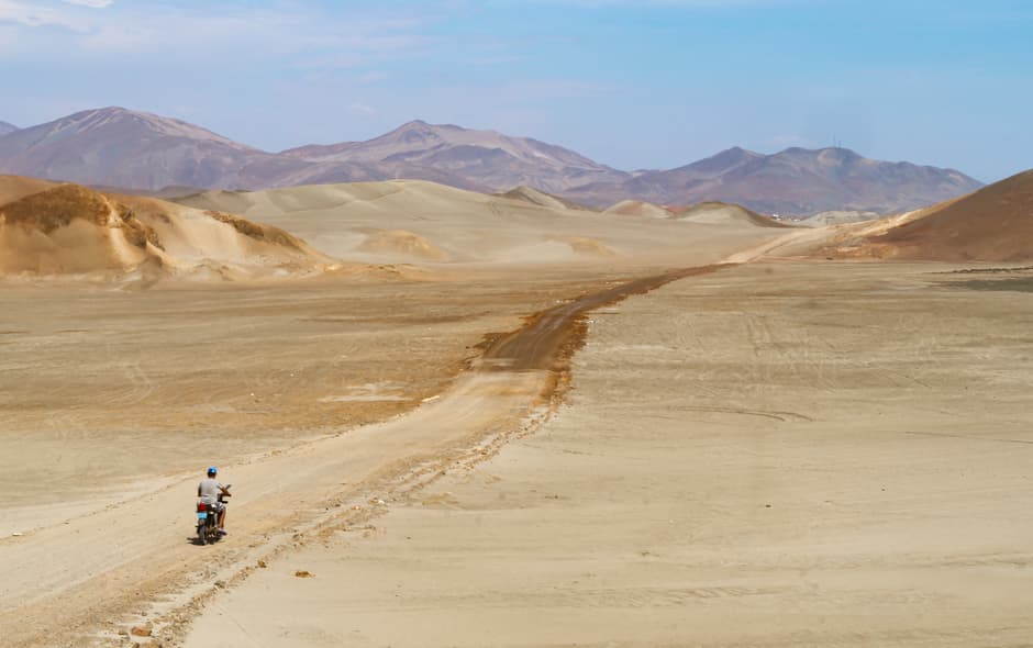 Hombre en bicicleta por una carretera del desierto, en el chat de Huarmey