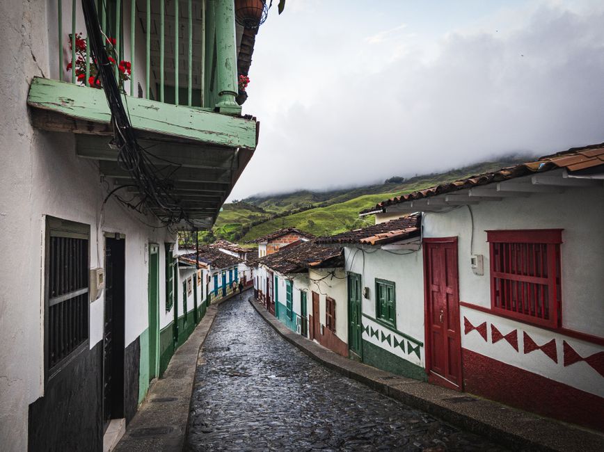 Calle empedrada con casas coloridas y árboles, en la sala de chat de Malambo