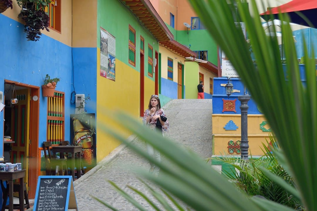Una persona camina por una calle de edificios de colores vivos, en el chat de Villanueva