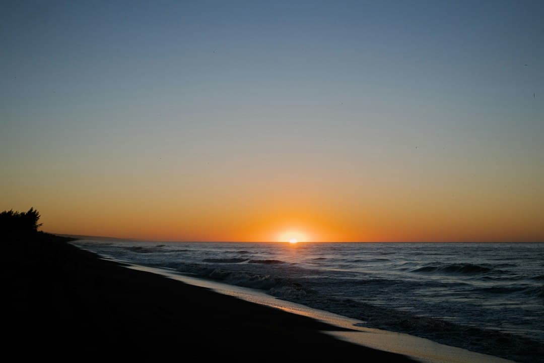 Puesta de sol sobre el mar con la orilla en sombra, en el chat de Iztapa