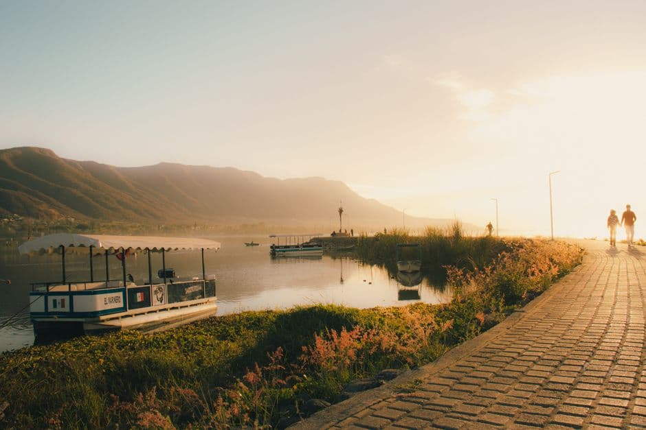 Barcas amarradas en la orilla y gente paseando al atardecer, en el chat de Jocotepec