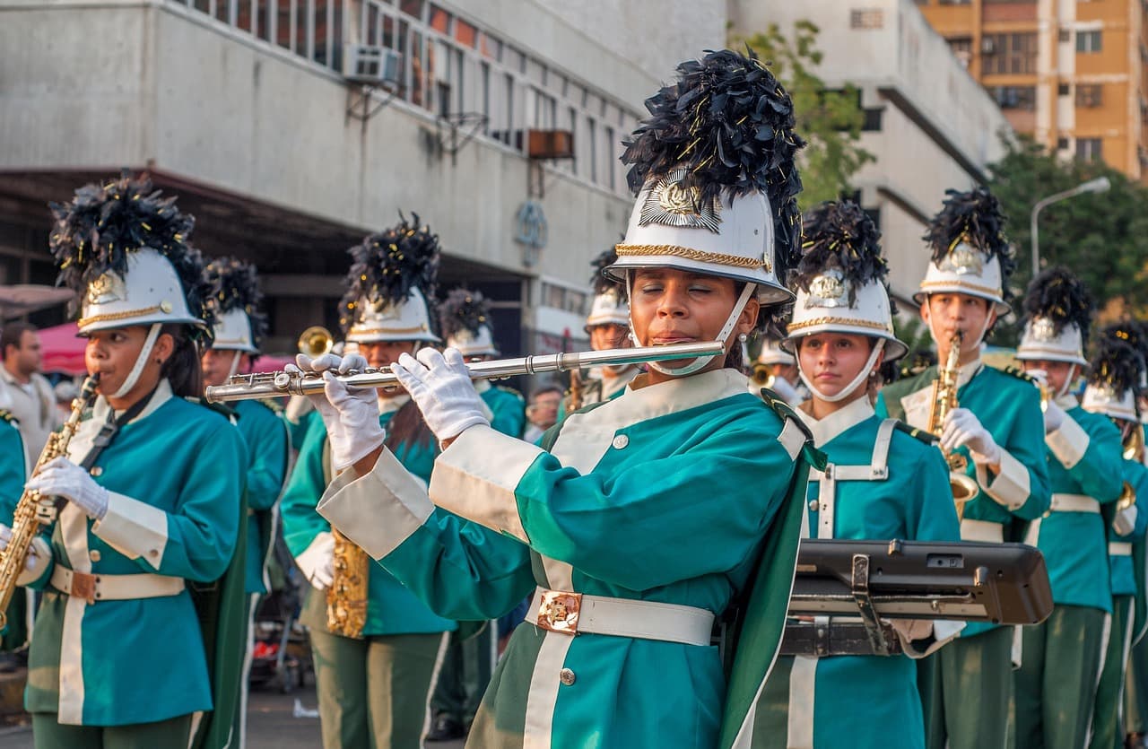 Banda tocando en una calle de pueblo venezolano, gente observando, en el chat de Uribante