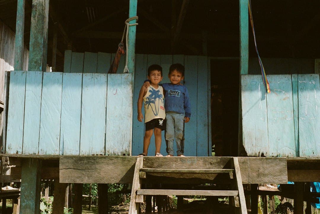 Dos niños pequeños de pie en un porche de madera, en el chat de Nauta