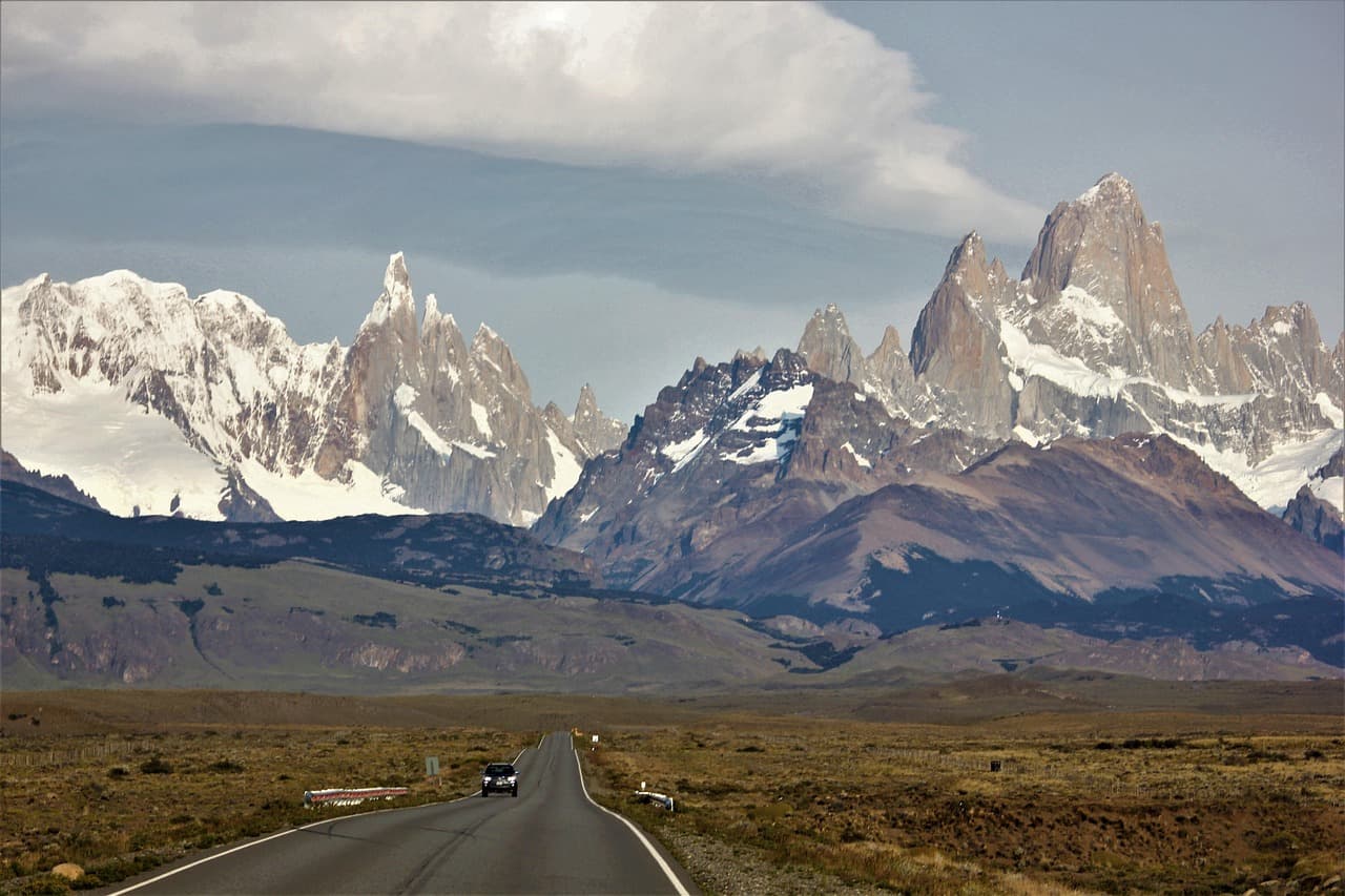 Carretera entre campos con montañas nevadas, en el chat de Daireaux