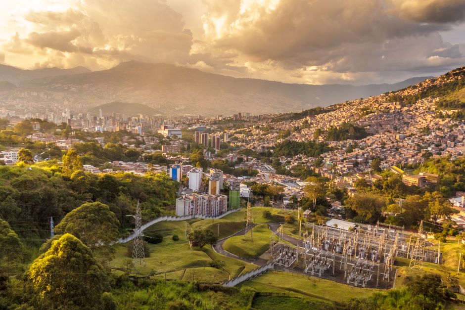 Ciudad colonial sobre colina verde con casas coloridas, en la sala de chat de Cereté