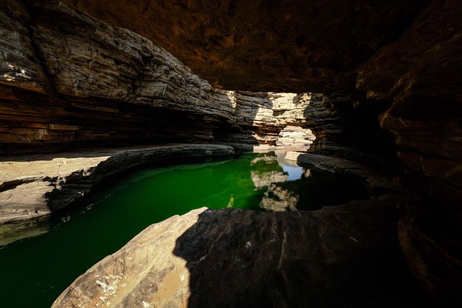 Poza de agua verde dentro de una cueva con rocas, en el chat de Pozo Colorado