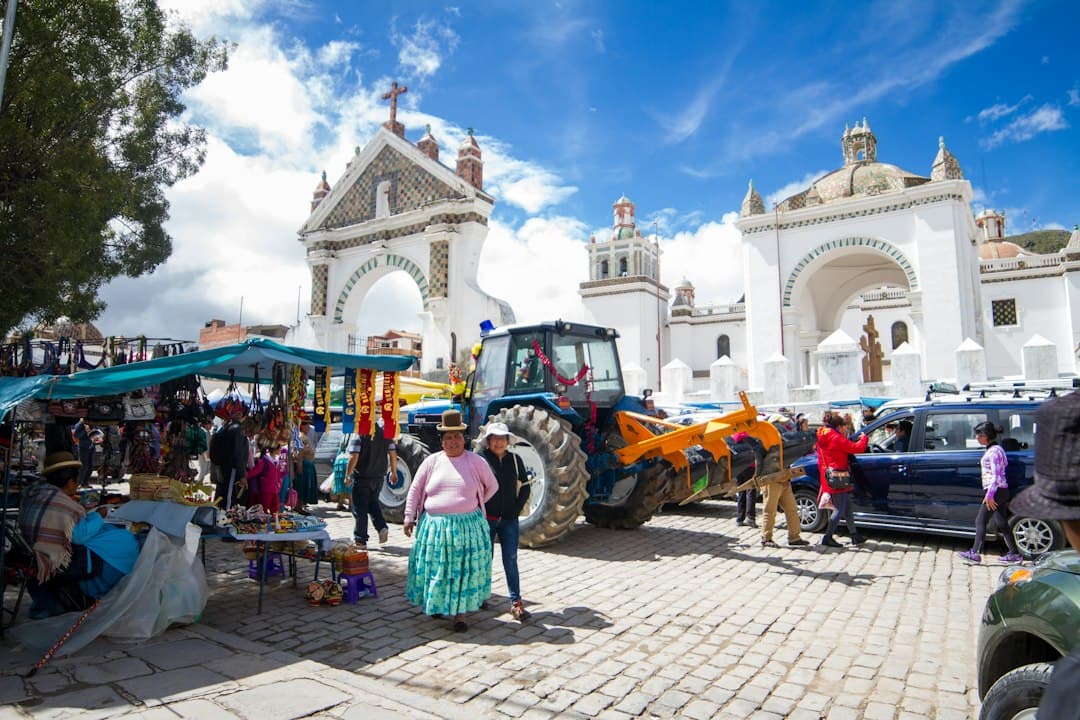 Tractor y puestos de mercado frente a edificios blancos, en el chat de Comarapa