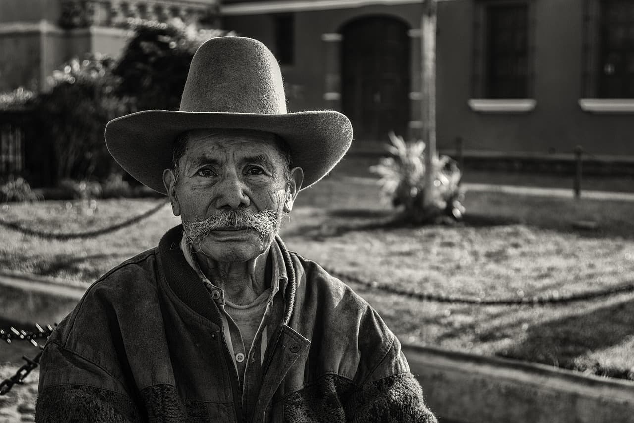Hombre guatemalteco con camisa tradicional y sombrero, mirando al frente, en el chat de Sibinal