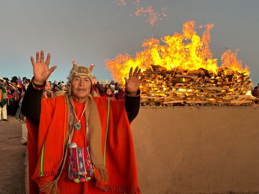 Hombre mayor de pie ante un fuego durante una ceremonia, en el chat de Jesús de Machaca