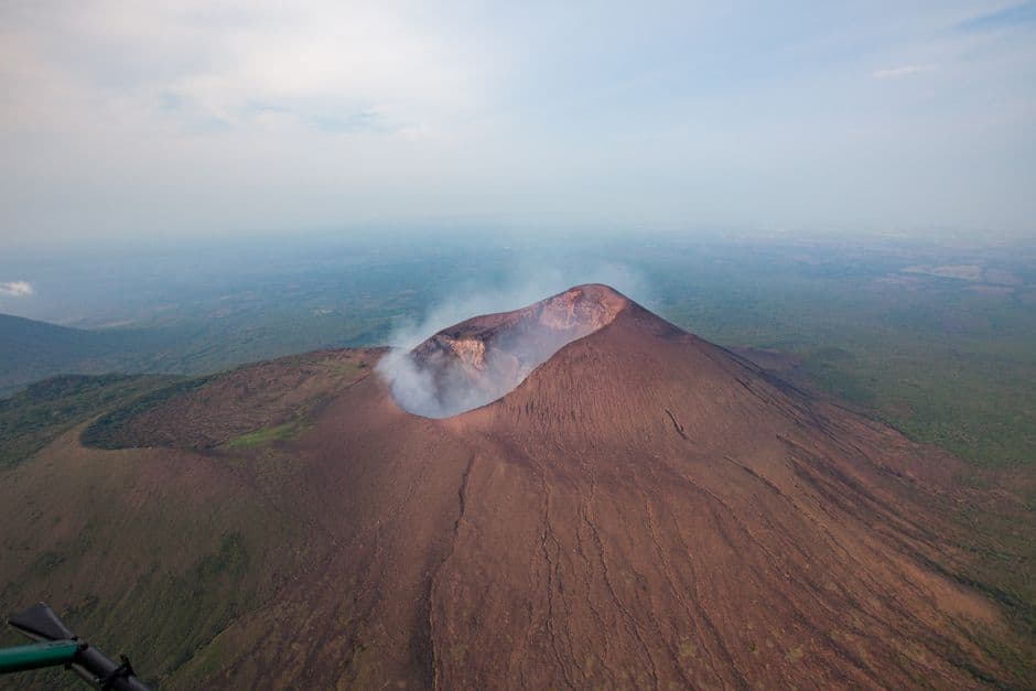 Vista aérea de un volcán pardo con humo blanco, en el chat de Santo Tomás