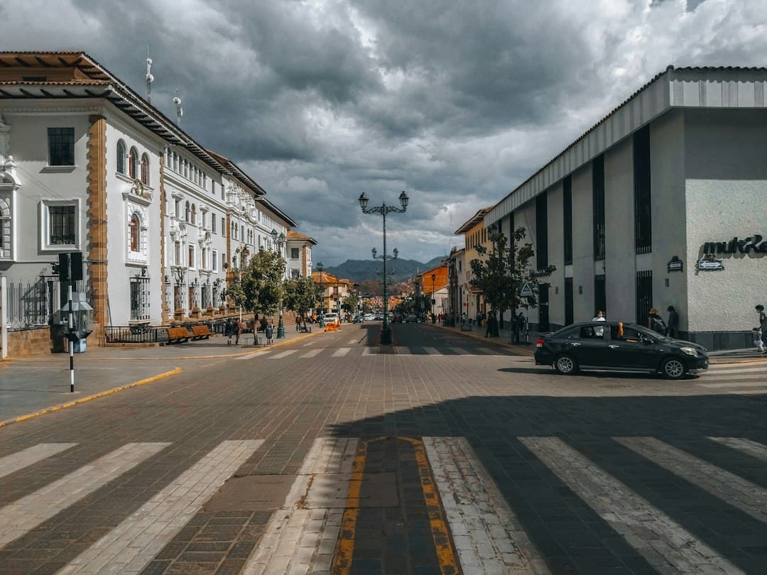 Coche negro circulando por una calle entre edificios altos, en el chat de Tocache