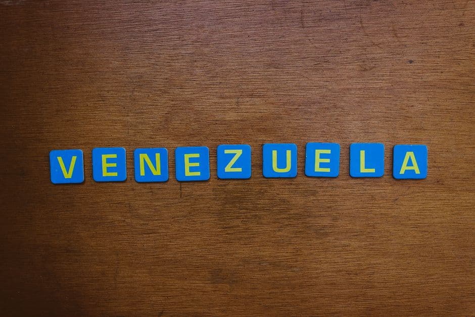 Fichas de Scrabble azules y amarillas sobre una superficie de madera, en la sala de chat de Carúpano