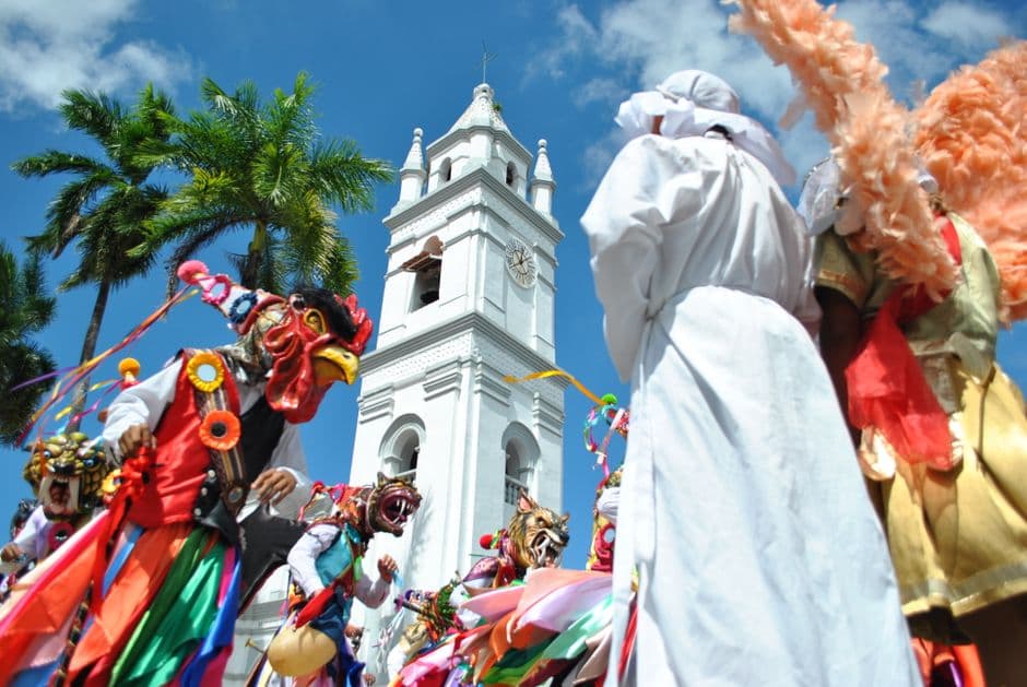 Personas disfrazadas desfilando cerca del campanario de una iglesia, en el chat de La Yarada-Los Palos