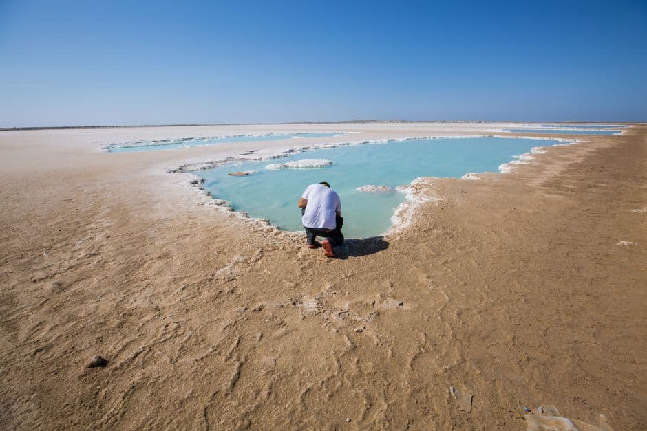 Hombre arrodillado a la orilla del agua, en el chat de Guerrero Negro