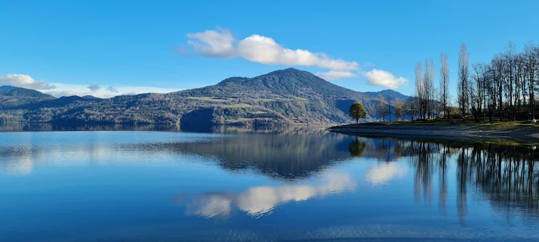 Lago junto a una montaña bajo un cielo azul de día, en el chat de Futrono