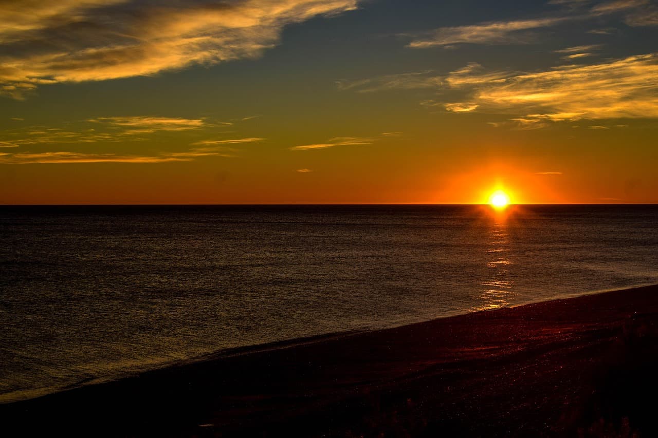 Amanecer sobre el mar con el sol saliendo del horizonte, en el chat de Comodoro Rivadavia