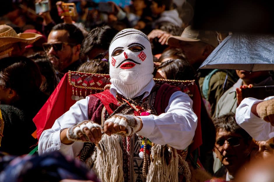 Hombre andino con vestimenta tradicional y sombrero de plumas, en la sala de chat de Paucartambo