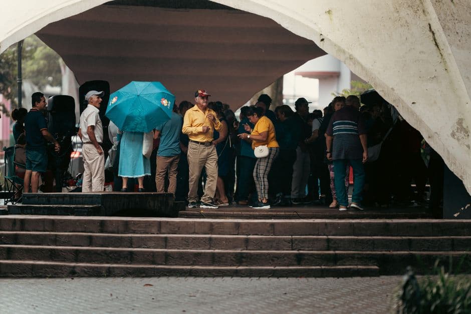 Personas bajo una gran cúpula, con paraguas, mientras llueve, en el chat de León Cortés Castro
