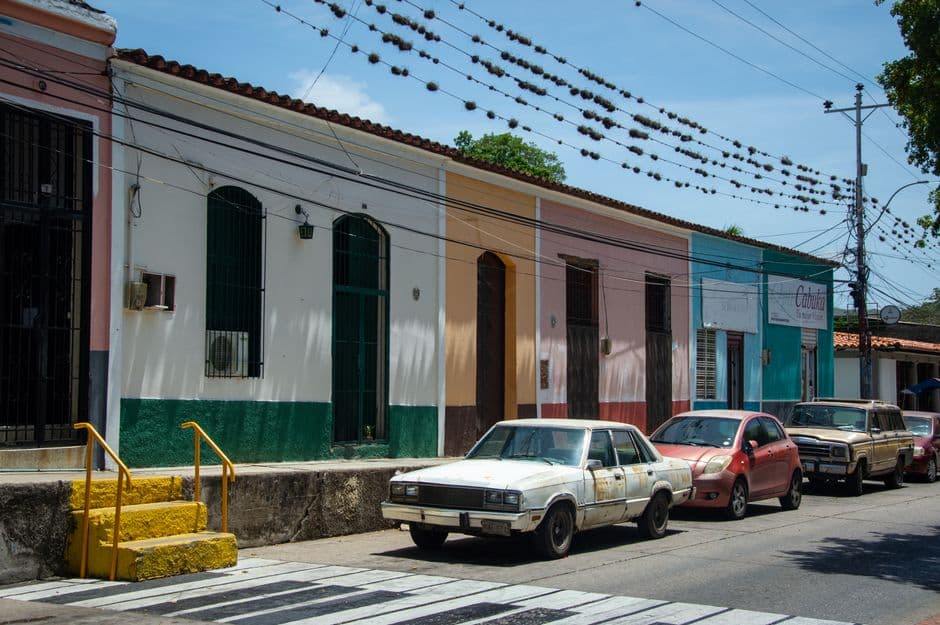 Coches aparcados en una calle junto a un edificio de colores, en el chat de El Almendro