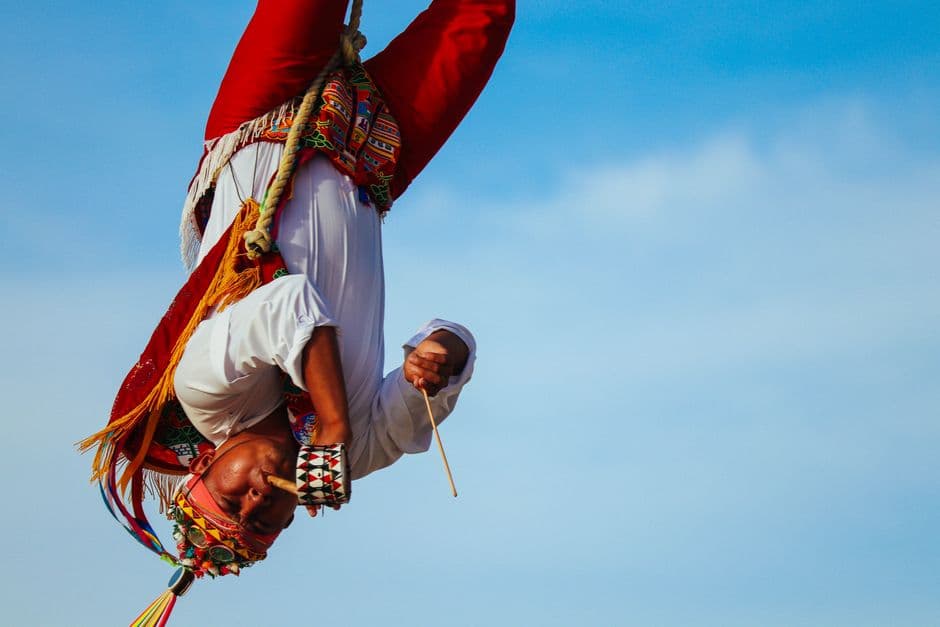Cuatro voladores en trajes tradicionales girando bajo el cielo azul, en el chat de Taraco