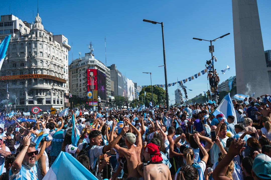 Un grupo de personas celebra en una plaza urbana llena de vida, en el chat de Juan María Gutiérrez (Buenos Aires)
