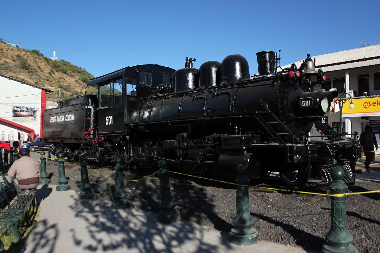 Tren de vapor cruzando la vía entre montañas, en el chat de Nacozari de García