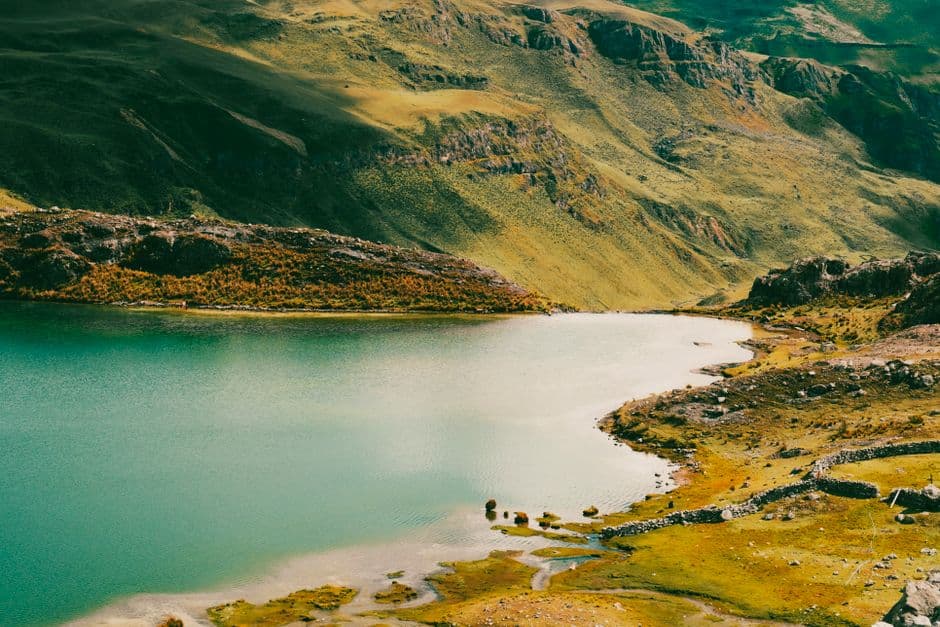 Lago de montaña entre colinas verdes bajo cielo azul, en la sala de chat de Quelloúno