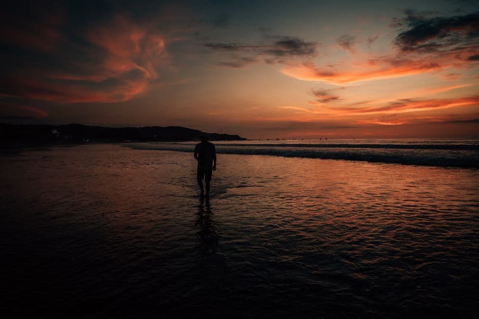 Silueta de un hombre caminando por la playa al anochecer, en el chat de Máncora