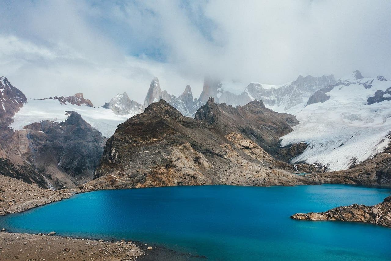 Lago rodeado de montañas nevadas bajo un cielo claro, en el chat de El Trébol