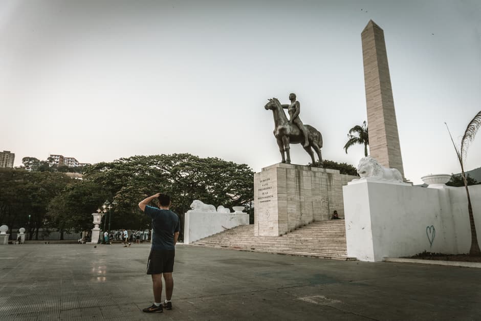 Un hombre de pie junto a una estatua, en el chat de Girardot