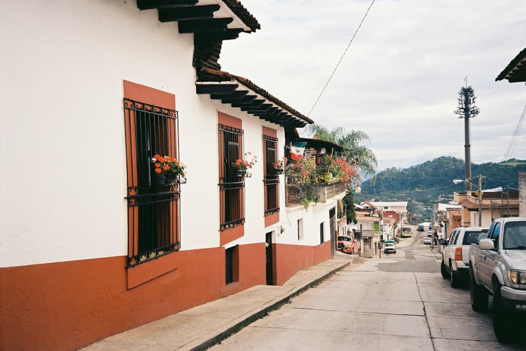 Una calle con edificios blancos y rojos y coches aparcados, en el chat de Huandacareo