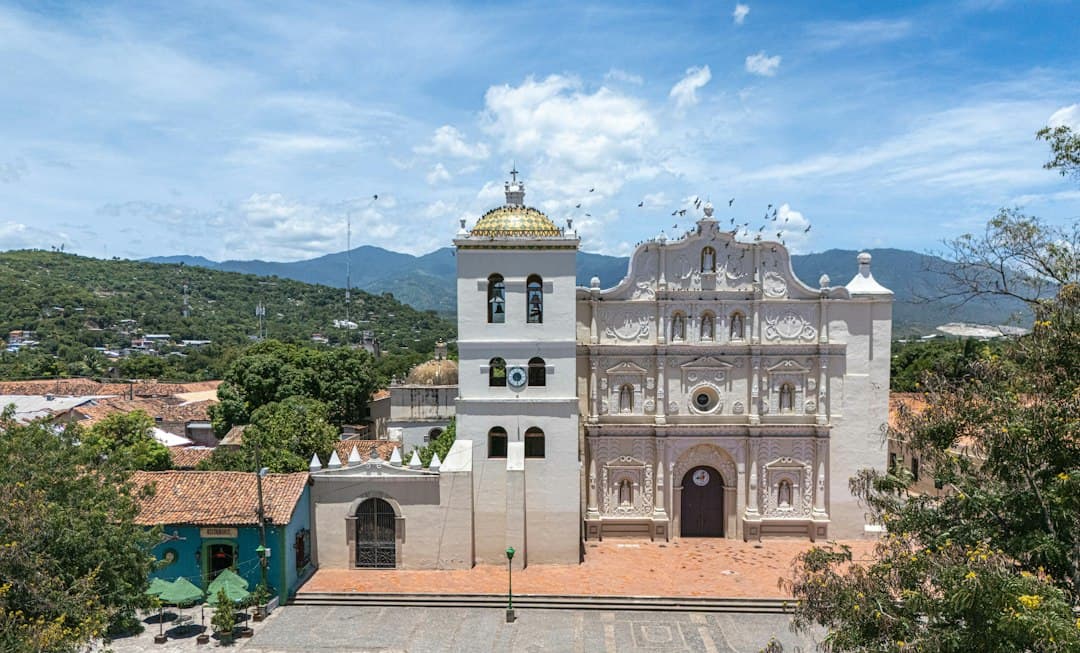 Iglesia colonial con cúpula dorada y montañas, en el chat de Ajuterique