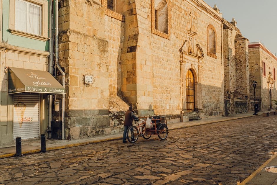 Hombre con una bicicleta y remolque en una calle vacía, en el chat de Tezoatlán de Segura y Luna