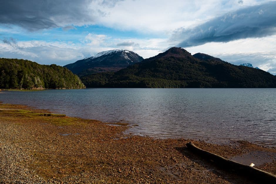 Lago de montaña en calma con picos nevados al fondo, en el chat de San Patricio del Chañar