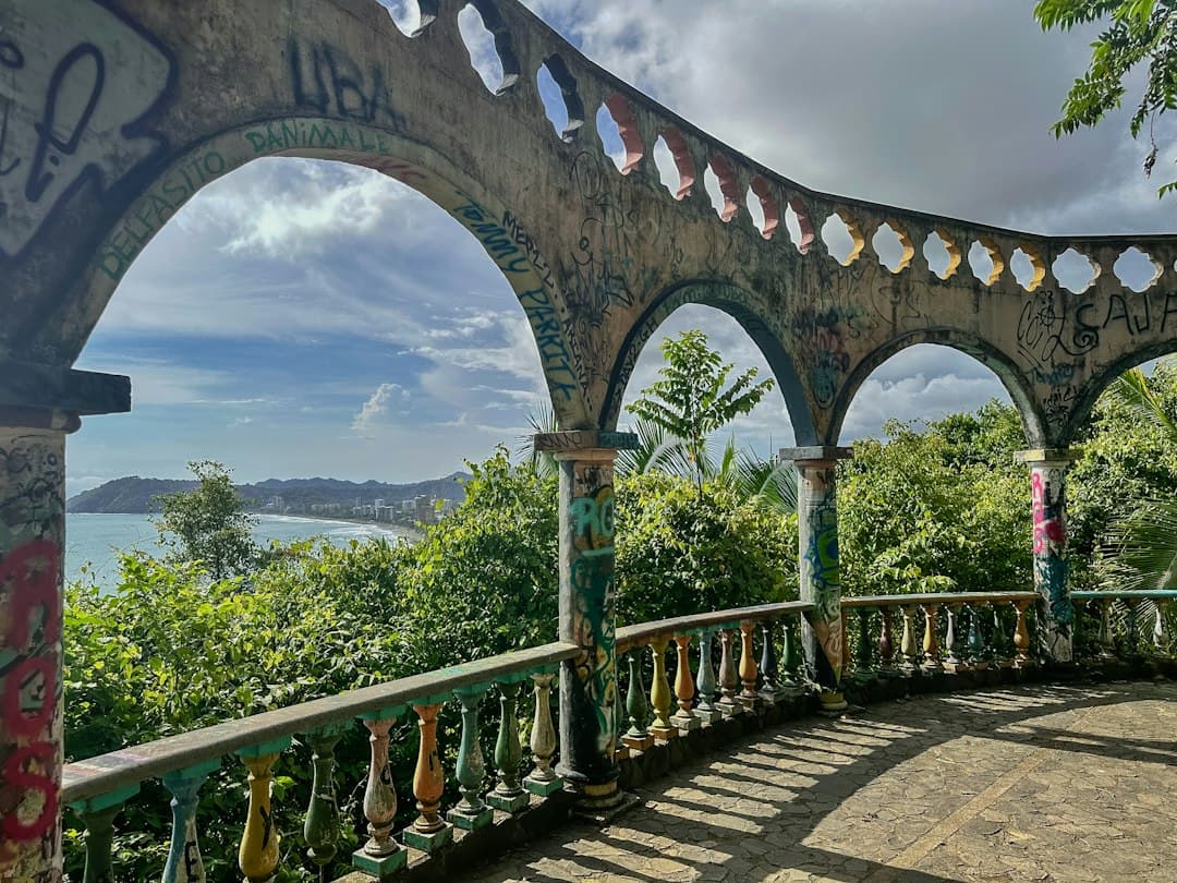 Ruinas con arcos frente a un paisaje verde y el océano, en el chat de Orotina