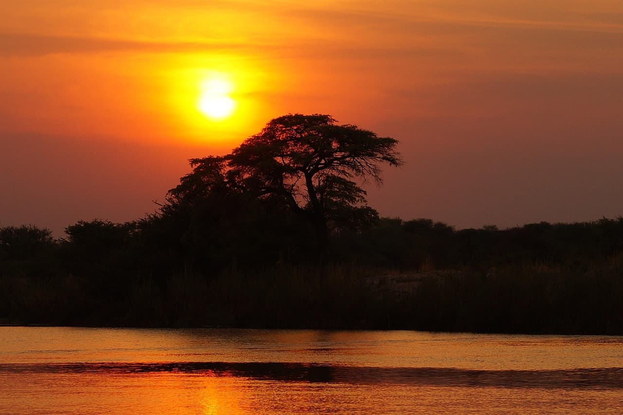 Puesta de sol sobre un río bordeado de árboles, en el chat de Juan Millán