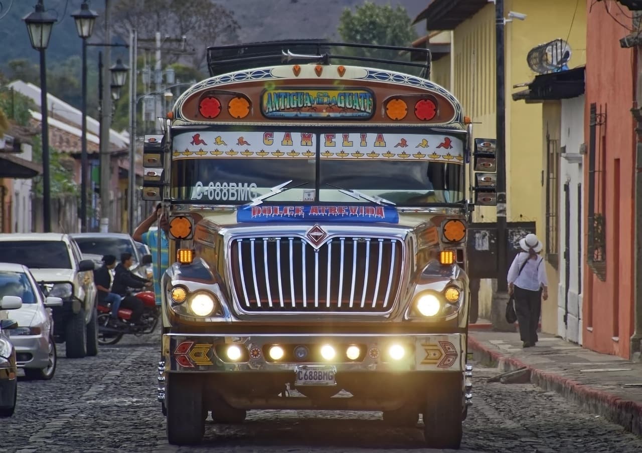 Autobús antiguo de colores desgastados detenido frente a casas coloniales, en el chat de Zapotitlán