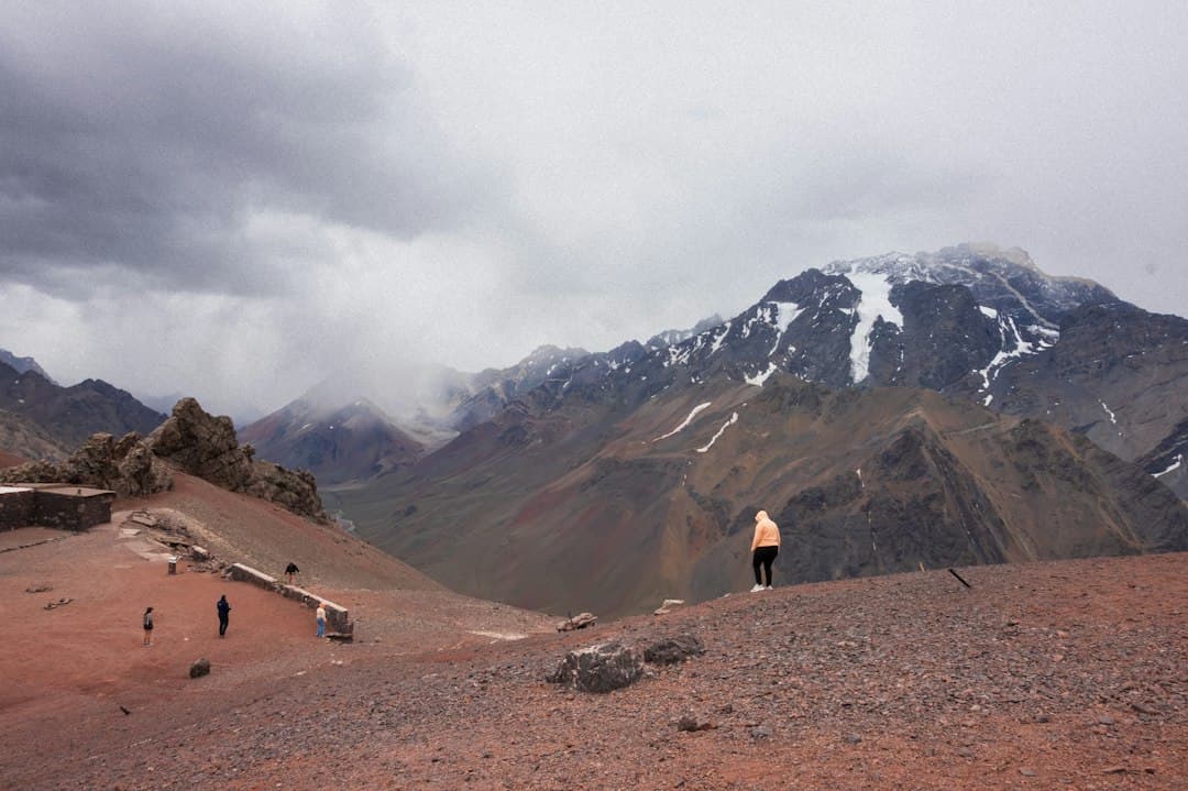 Persona de pie en una montaña frente a una cordillera nevada, en el chat de Frontera