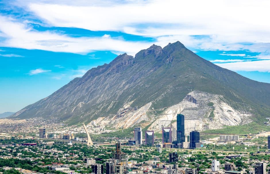 Una majestuosa montaña se alza sobre moderna ciudad, en el chat de San Pedro Garza García