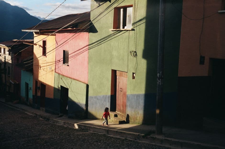 Niño caminando por la acera cerca de casas coloridas, en la sala de chat de La Paz