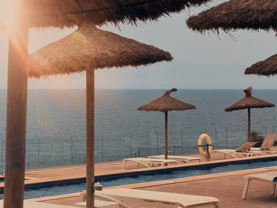 Tumbonas y sombrillas junto a una piscina con vistas al mar, en la sala de chat de Manacor
