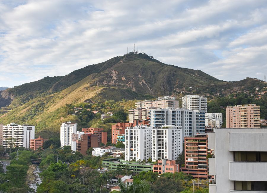 Edificios altos cerca de una montaña verde en la sala de chat de Cali
