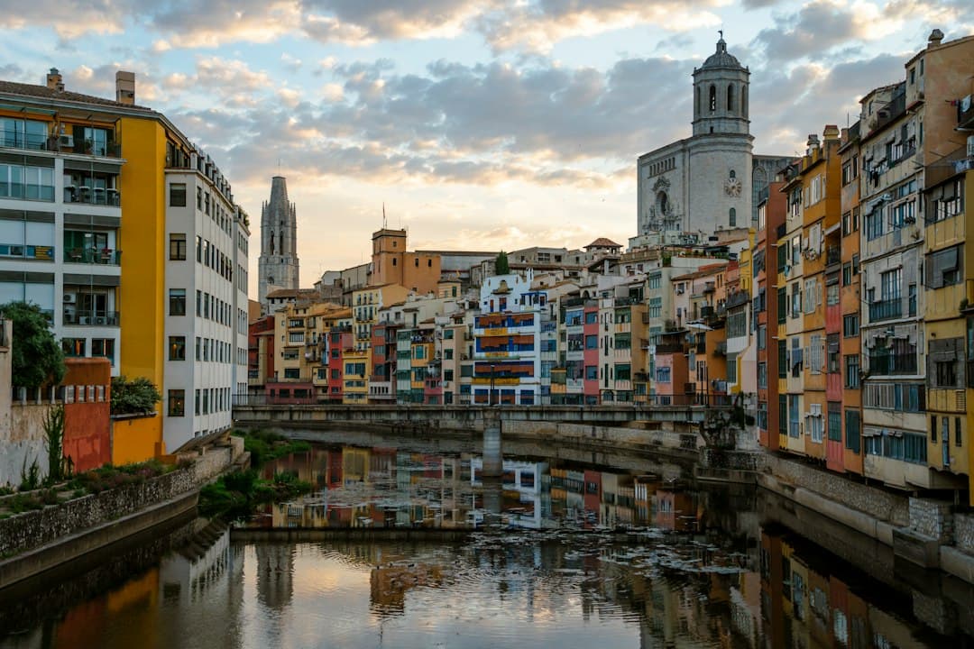 Edificios coloridos bordean un río bajo un cielo claro, en el chat de Illescas
